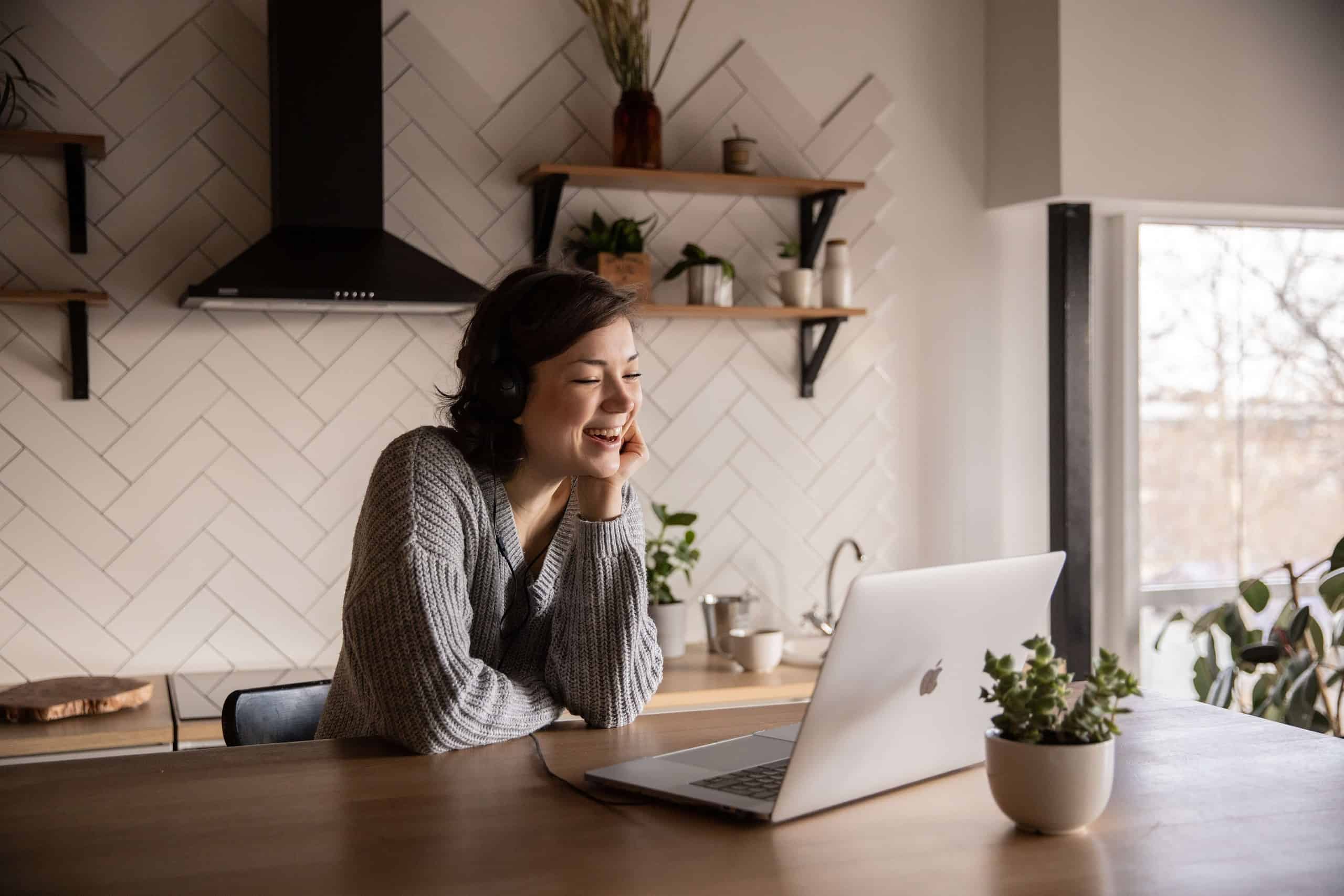 A smiling woman on a video call connecting with her ideal client and addressing their pain points.